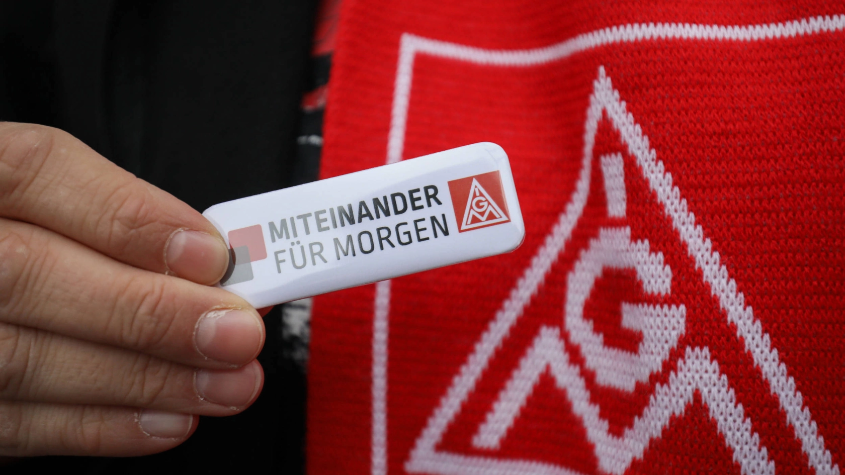 Jemand hält einen Anstecker mit der Aufschrift "miteinander für morgen".