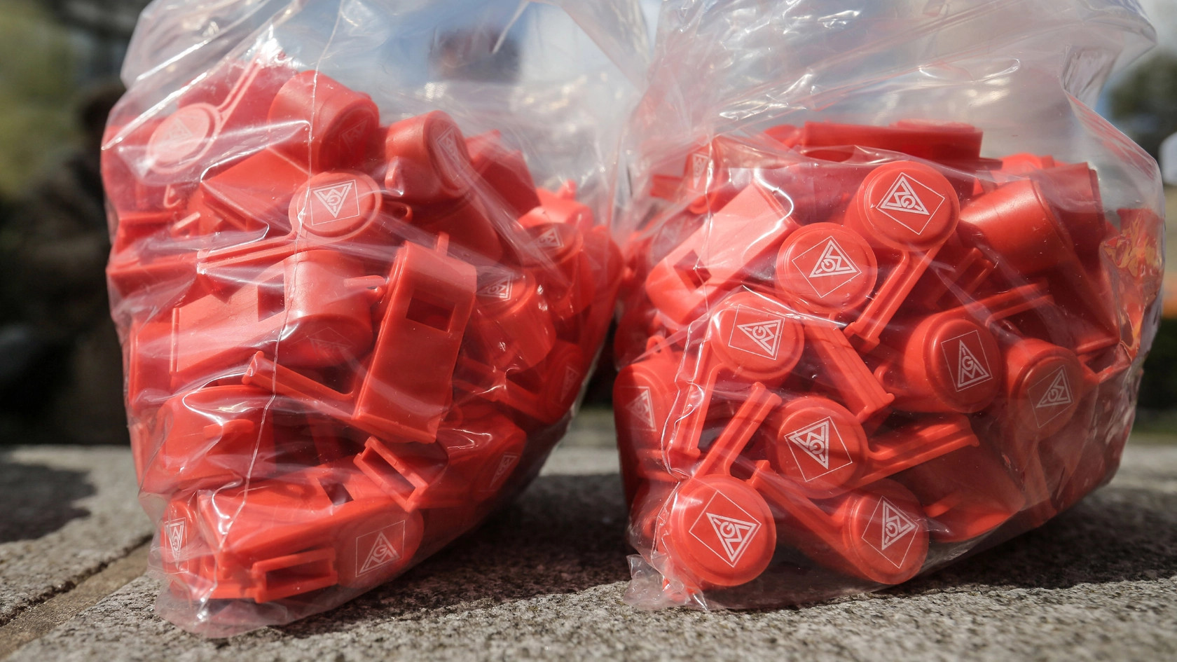 Rote IG Metall-Pfeifen in zwei Plastiktüten.